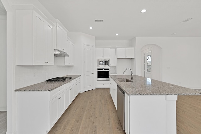 kitchen featuring light wood finished floors, visible vents, appliances with stainless steel finishes, a sink, and under cabinet range hood