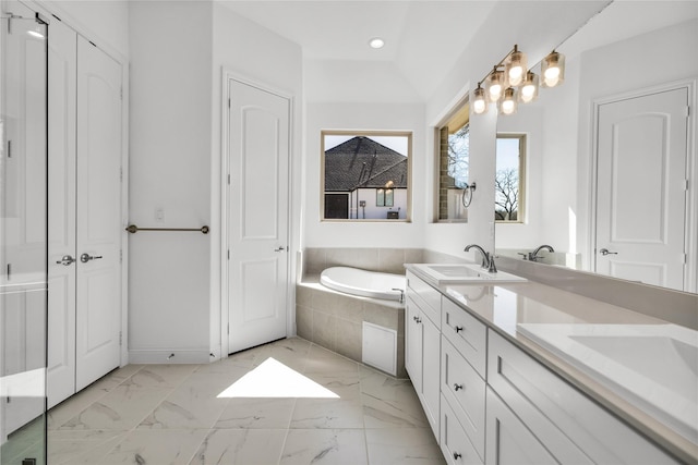 bathroom with a sink, vaulted ceiling, marble finish floor, a bath, and double vanity