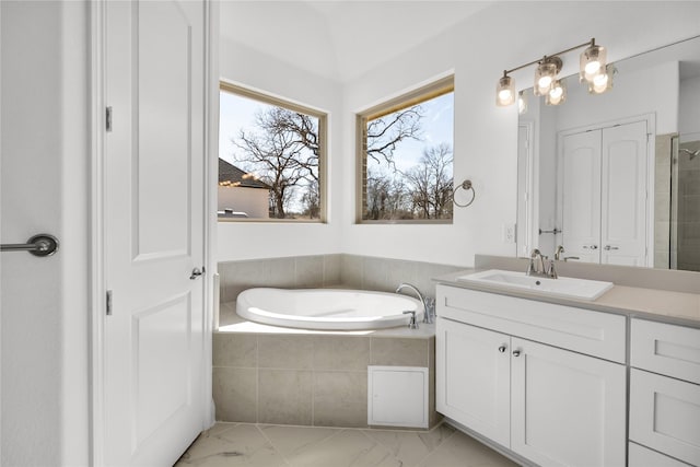 bathroom with marble finish floor, a bath, and vanity