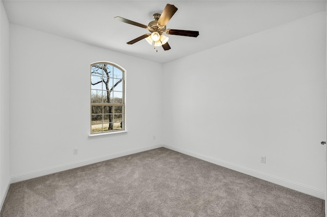 carpeted spare room featuring baseboards and a ceiling fan