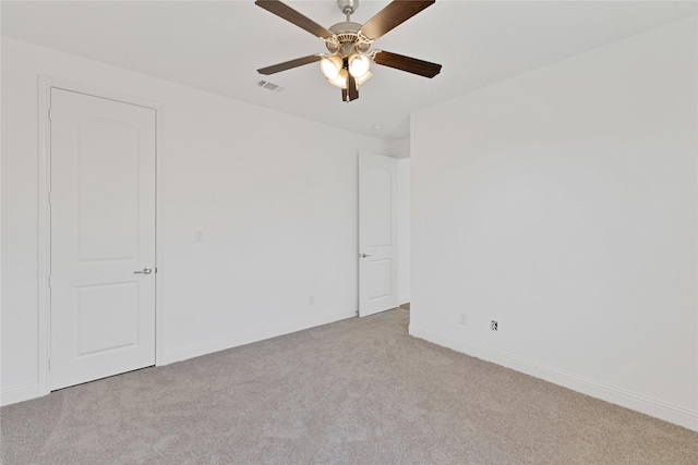 carpeted spare room featuring a ceiling fan, visible vents, and baseboards