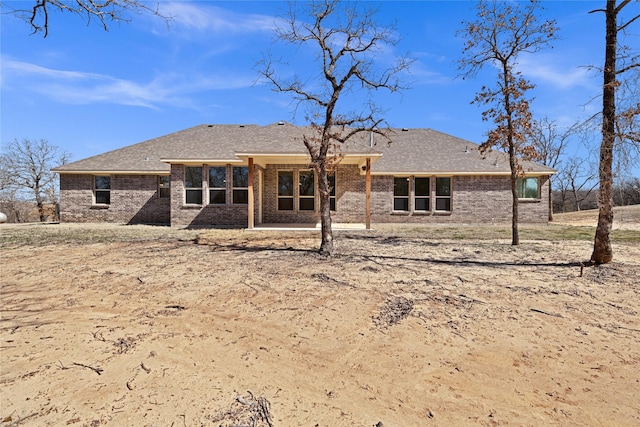 rear view of property featuring a patio, brick siding, and a shingled roof