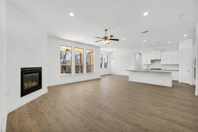 unfurnished living room with recessed lighting, wood finished floors, visible vents, a ceiling fan, and a glass covered fireplace