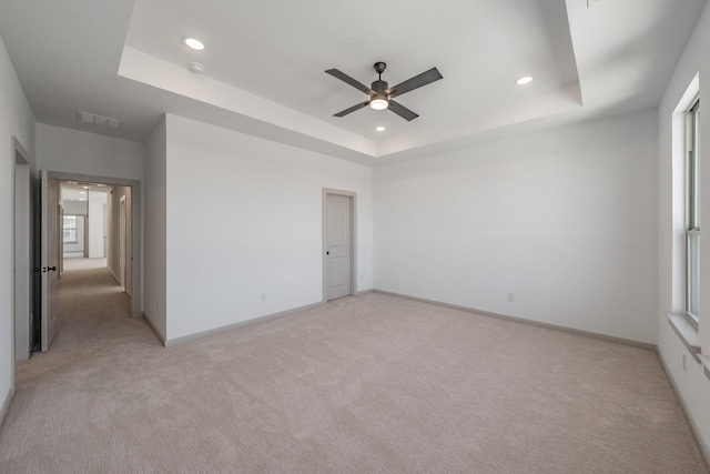 unfurnished room with a raised ceiling, visible vents, light carpet, and baseboards