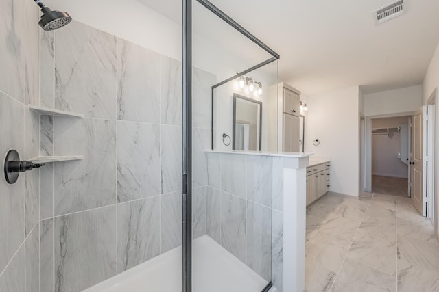 full bath featuring vanity, visible vents, marble finish floor, a stall shower, and a walk in closet