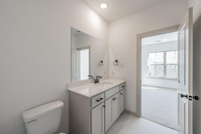 half bath featuring tile patterned floors, vanity, toilet, and baseboards