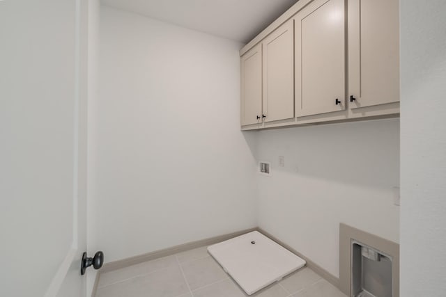 clothes washing area featuring cabinet space, hookup for a washing machine, baseboards, and tile patterned floors