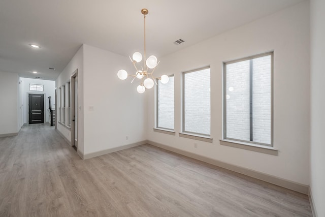 unfurnished room with a chandelier, visible vents, light wood-style flooring, and baseboards