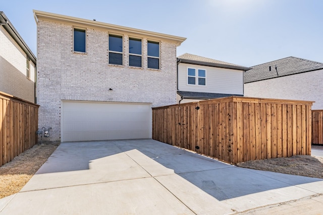 exterior space with a garage, driveway, fence, and brick siding