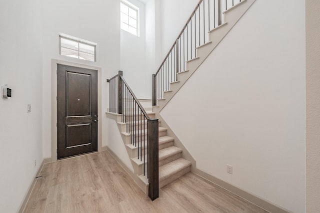 entryway featuring stairway, wood finished floors, a towering ceiling, and baseboards