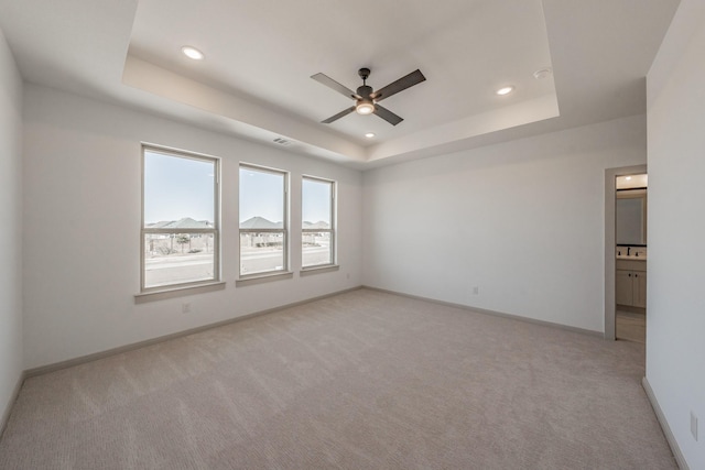 unfurnished room with a tray ceiling, recessed lighting, a ceiling fan, light carpet, and baseboards