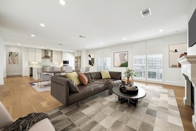 living area featuring light wood finished floors, a fireplace, visible vents, and recessed lighting