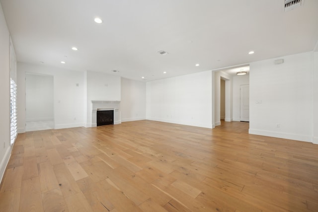 unfurnished living room with recessed lighting, a fireplace, visible vents, baseboards, and light wood-style floors