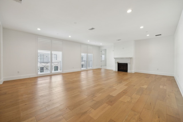 unfurnished living room with recessed lighting, a fireplace, and light wood-style floors