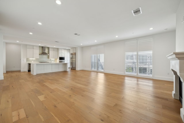 unfurnished living room featuring light wood-type flooring, visible vents, a fireplace, and recessed lighting