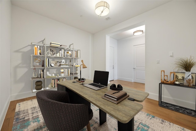 office featuring visible vents, baseboards, and wood finished floors