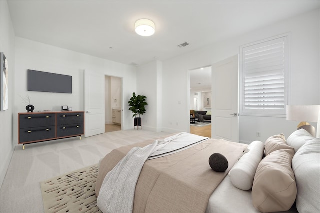 bedroom featuring light carpet, connected bathroom, visible vents, and baseboards