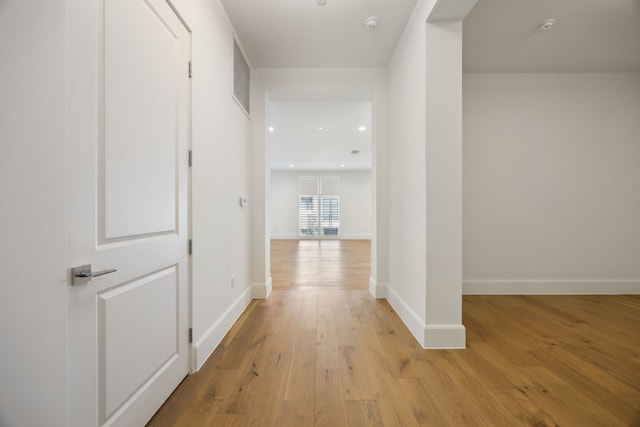 hall with light wood-style flooring and baseboards