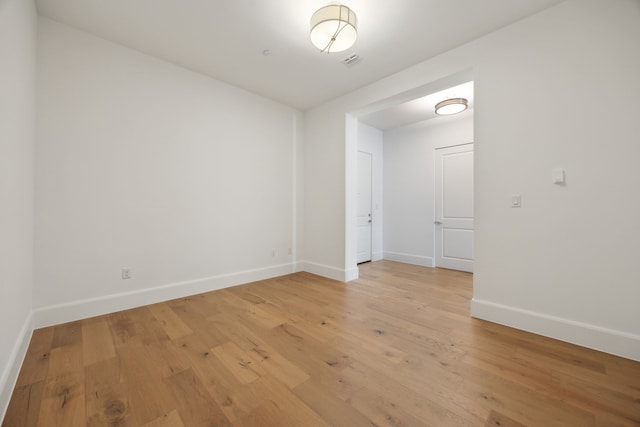 spare room with light wood-style flooring, visible vents, and baseboards