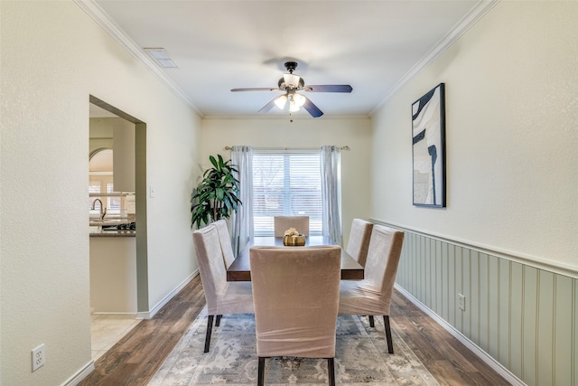 dining area featuring a ceiling fan, visible vents, crown molding, and wood finished floors