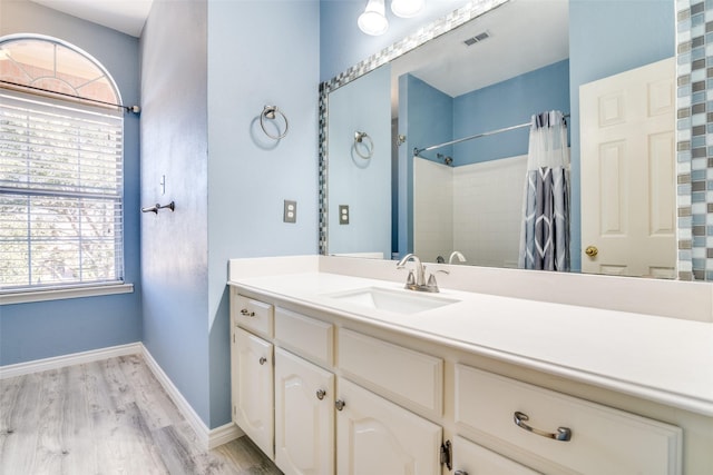 bathroom featuring a shower with shower curtain, wood finished floors, vanity, visible vents, and baseboards