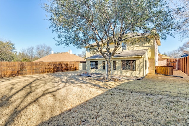 back of property with a fenced backyard and a lawn