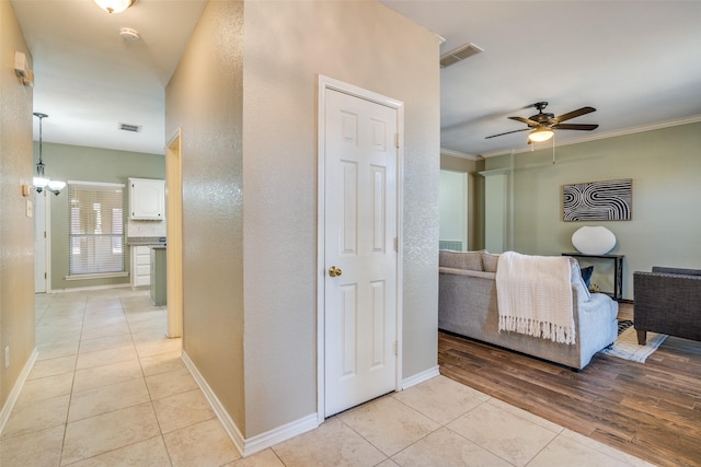 hall featuring visible vents, ornamental molding, baseboards, and light tile patterned flooring