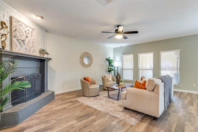 living room featuring ornamental molding, a brick fireplace, and wood finished floors