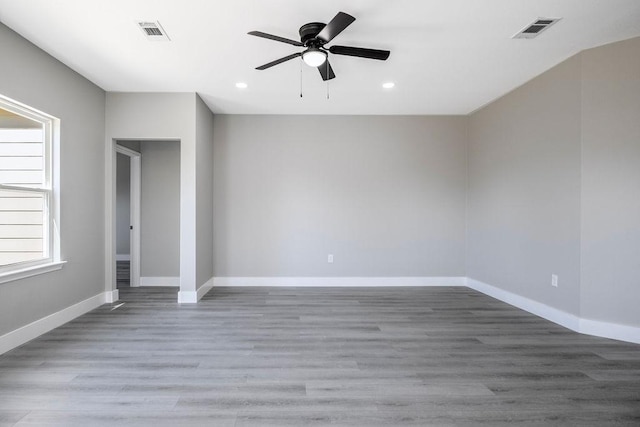 empty room with baseboards, visible vents, ceiling fan, and wood finished floors