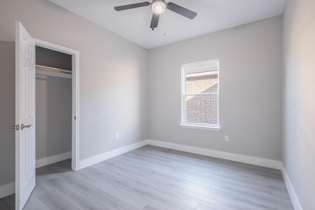 unfurnished bedroom featuring light wood-type flooring, a closet, baseboards, and a ceiling fan