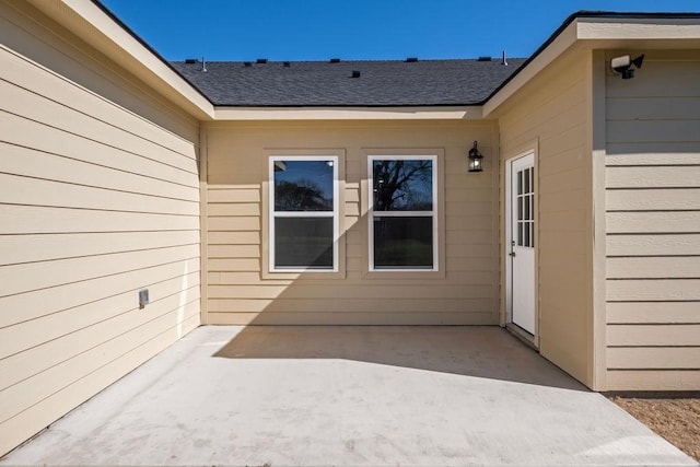 property entrance featuring a patio and a shingled roof