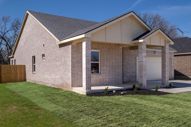 view of front of house featuring brick siding, a front lawn, an attached garage, and fence