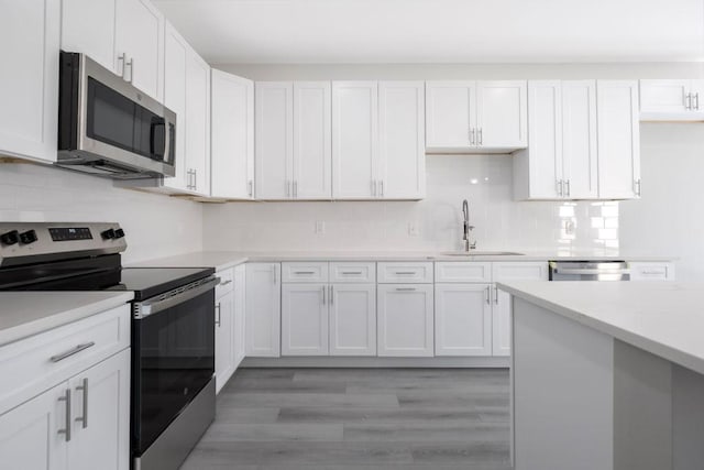 kitchen featuring appliances with stainless steel finishes, a sink, and white cabinets