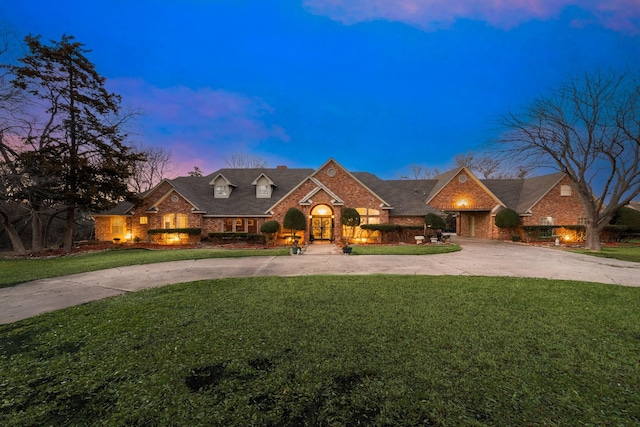 view of front of property with concrete driveway, brick siding, and a front lawn