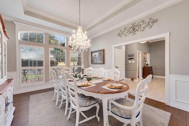 dining area featuring a raised ceiling, a wainscoted wall, and dark wood-style flooring