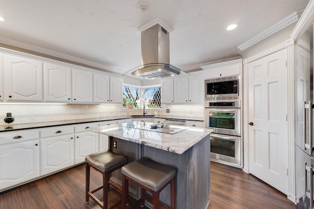 kitchen with appliances with stainless steel finishes, ornamental molding, a breakfast bar area, island exhaust hood, and a sink