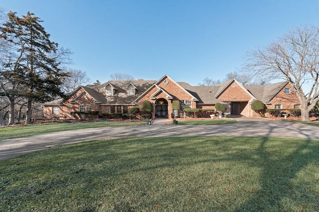 view of front of house featuring brick siding, concrete driveway, and a front yard