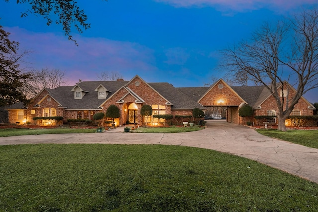 view of front facade with concrete driveway, a front lawn, and brick siding