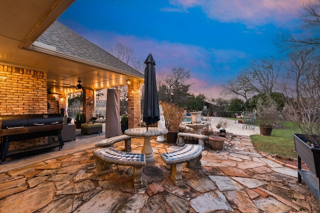 patio terrace at dusk with a grill and a ceiling fan