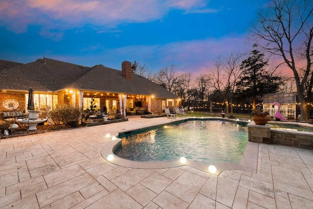 pool at dusk featuring a patio area and an outdoor pool