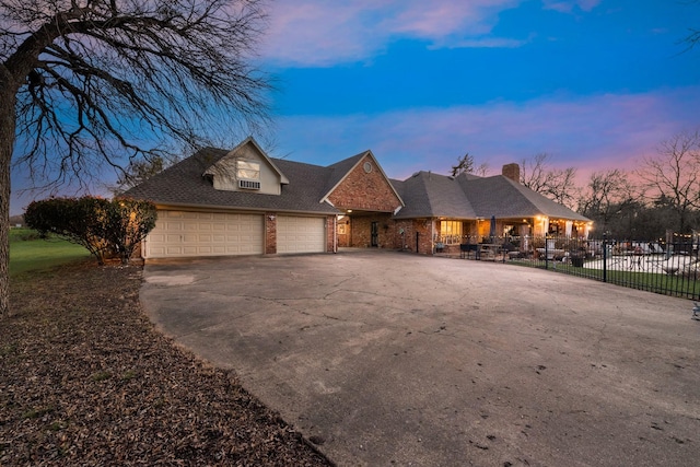 view of front facade with brick siding, driveway, an attached garage, and fence