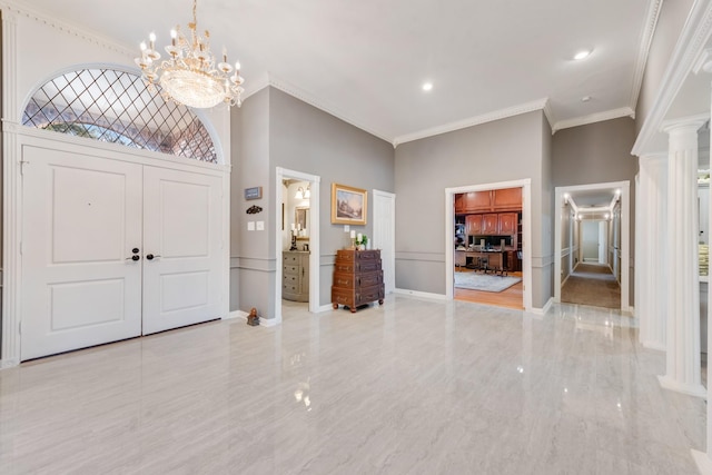 entryway with decorative columns, baseboards, ornamental molding, an inviting chandelier, and a high ceiling