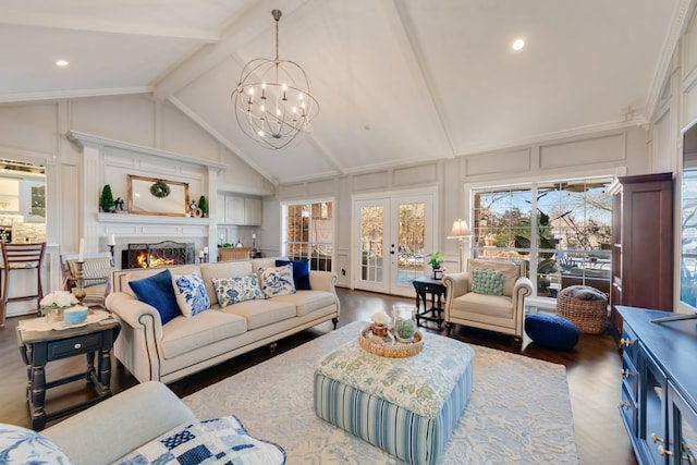 living area featuring wood finished floors, a lit fireplace, a chandelier, a decorative wall, and beam ceiling