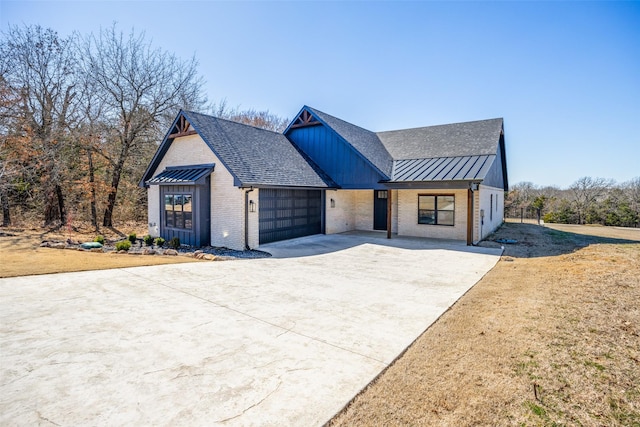 modern inspired farmhouse with driveway, a garage, metal roof, a standing seam roof, and brick siding