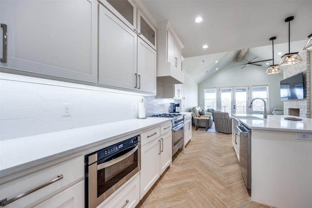 kitchen featuring decorative backsplash, open floor plan, stainless steel appliances, light countertops, and white cabinetry