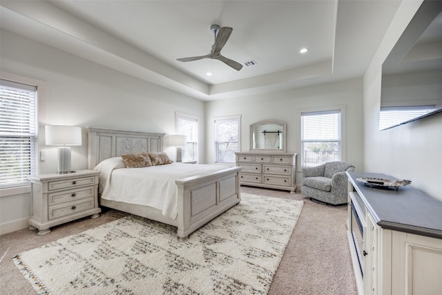 bedroom featuring light carpet, visible vents, baseboards, a tray ceiling, and recessed lighting