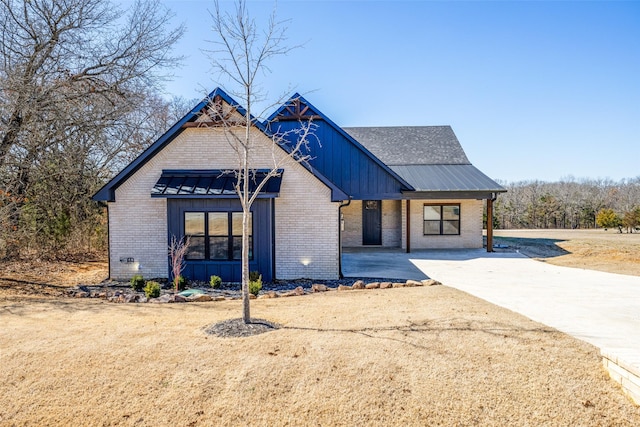 modern farmhouse style home with metal roof, brick siding, a standing seam roof, and board and batten siding