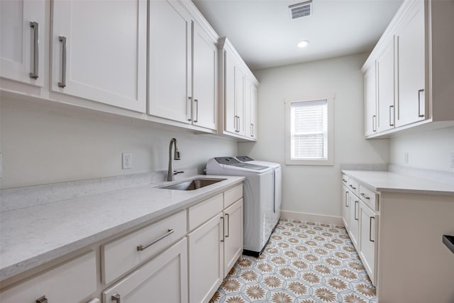 laundry room with a sink, visible vents, baseboards, cabinet space, and washing machine and clothes dryer