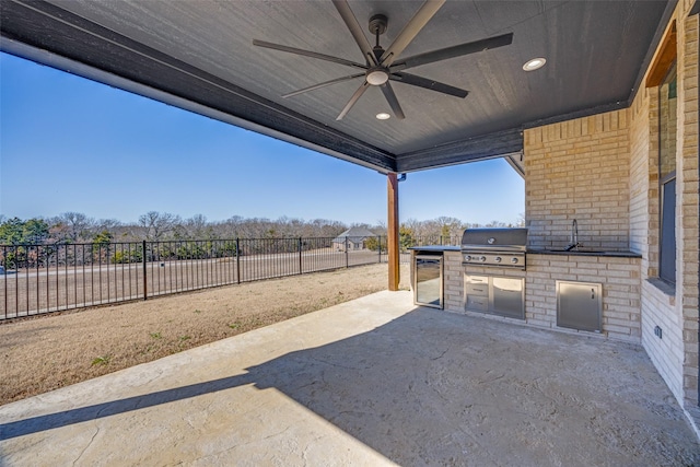 view of patio featuring ceiling fan, a fenced backyard, a sink, a grill, and exterior kitchen