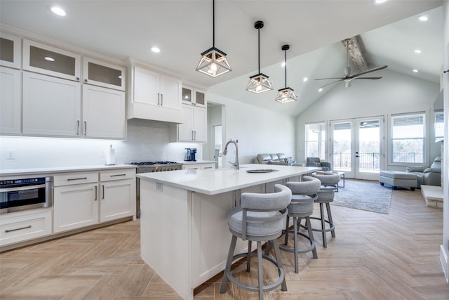 kitchen with french doors, light countertops, open floor plan, stainless steel oven, and high vaulted ceiling